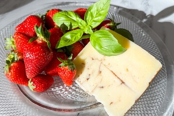 Sunlit strawberries embrace basil-topped cheese, evoking Midsummer Night's picnic, culinary fusion...
