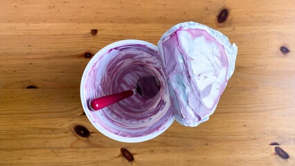 Empty yogurt cup swirled with berry remnants, whispering post-dessert nostalgia, captures essence...