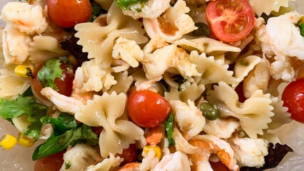 Shrimp and bow-tie pasta tango amidst vibrant cherry tomatoes, ideal for Pesce Week feasts or...