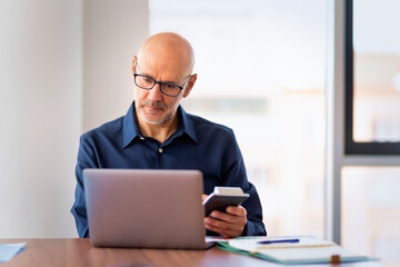 Professional man sitting in a modern office and using laptop computer
