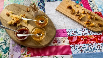 Patchwork tablecloth whispers nostalgia beneath golden crumbles and jewel-toned jams, evoking cozy...