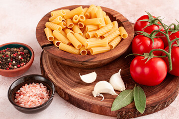 Pasta ingredients spread out, on a wooden surface, with tomatoes and spices, ready to cook, there are no people