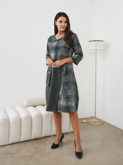 Elegant woman posing in stylish dress within a modern indoor setting
