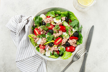 salad with canned tuna, vegetable salad with quail eggs, lettuce and romaine leaves, red onion, cherry tomatoes, olives, keto food, healthy eating,
