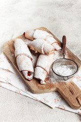 bagels with filling, sweet pastries, sprinkled with powdered sugar, on a wooden board, dessert, breakfast,