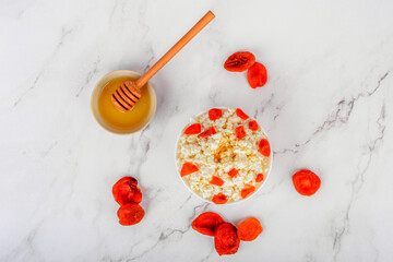 Top view of fresh cottage cheese with dried apricots and honey.