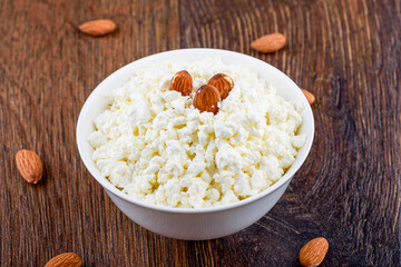 Fresh cottage cheese and some almonds in a white bowl.
