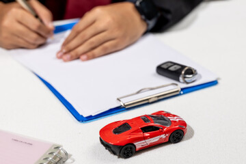 Finalizing Car Purchase – Man Signing Insurance Papers at Desk