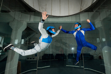 A male instructor teaches a woman how to fly in a wind tunnel. Free fall simulator.