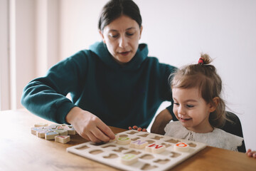 Mother teaches her little girl letters through play