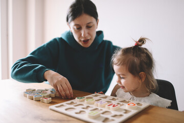 Mother teaches her little girl letters through playing the game