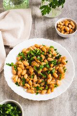 Homemade fried white beans and greens salad on plate on table vertical view