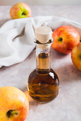 Fermented apple cider vinegar in glass bottle and fruits on table vertical view