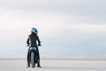 Obraz premium single motorbike enthusiast stands in wide expanse helmet on wearing casual riding gear