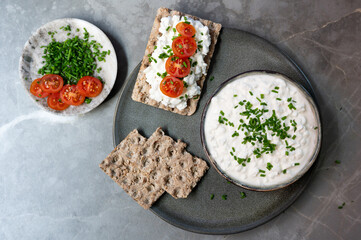 Morning snack featuring slices of crispy bread layered with cottage cheese and tomatoes on a plate.