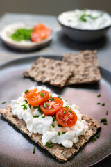 Open sandwiches made with crispbread, cottage cheese, and tomatoes on a gray plate.