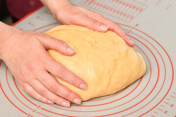 Hands of a female baker kneading dough for muffins, bread, buns close-up. Process of baking at home.