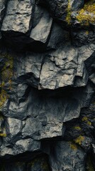 Fototapeta premium Dark, rough rock face, speckled with yellow lichen.