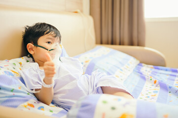 Boy 4 years old , inhale medication by inhalation mask to cure Respiratory Syncytial Virus (RSV) on hospital bed. Admitted patient boy inhalation therapy.