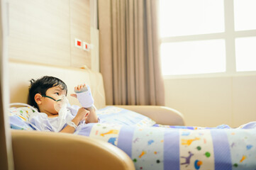 Boy 4 years old , inhale medication by inhalation mask to cure Respiratory Syncytial Virus (RSV) on hospital bed. Admitted patient boy inhalation therapy.