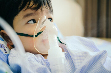 Boy 4 years old , inhale medication by inhalation mask to cure Respiratory Syncytial Virus (RSV) on hospital bed. Admitted patient boy inhalation therapy.