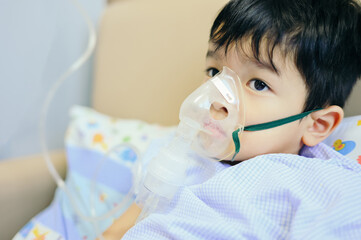 Boy 4 years old , inhale medication by inhalation mask to cure Respiratory Syncytial Virus (RSV) on hospital bed. Admitted patient boy inhalation therapy.
