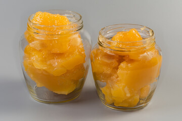 Crystallized white honey in two glass jars on gray background