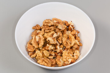 Seed kernels of walnuts in bowl on a gray background