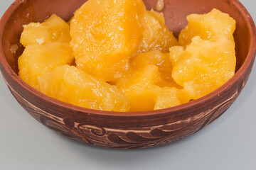 Crystallized white honey in clay bowl, fragment close-up