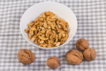 Seed kernels of walnuts in bowl and whole walnuts beside