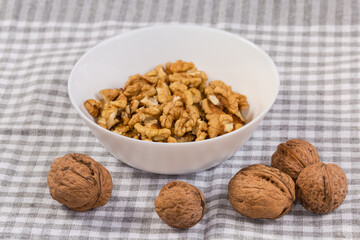 Whole walnuts against the shelled walnut seed kernels in bowl