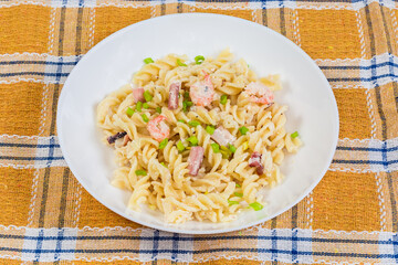 Spiral pasta with boiled seafood in white souse on dish