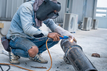 Worker with protective mask welding metal in workshop, man works with a welding machine, Flying...