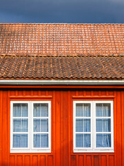 Fototapeta premium Unique red wooden building showcasing architectural details in Mölndal, Sweden on a cloudy day