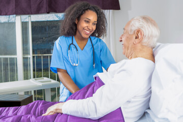 Smiling nurse comforting elderly patient lying in hospital bed during compassionate care moment