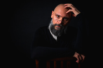 Thoughtful mature man with glasses and beard posing in studio with dramatic lighting. Conceptual...