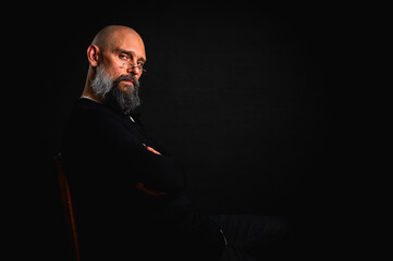 Funny close-up portrait of a quirky bald man with a long gray beard and eyeglasses, making a silly face. Concept of eccentricity, humor, and expressive personality.