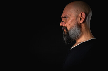 Fototapeta premium Funny close-up portrait of a quirky bald man with a long gray beard and eyeglasses, making a silly face. Concept of eccentricity, humor, and expressive personality.
