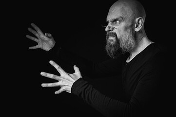 Black and white close-up portrait of a funny emotional weird bald man with a long gray beard and...