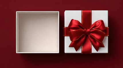 Top view of open white gift box with red satin ribbon bow on dark red background, elegant minimal composition