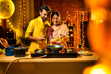 Pouring oil for cooking, Indian couple preparing festive food in kitchen on Diwali night