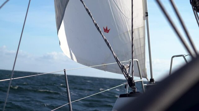 Sailboat at sea. The ocean appears choppy, with dark waves under a bright, mostly clear blue sky