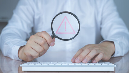 Businessman holding a magnifying glass hovering over a red triangle warning icon, symbolizing risk detection, data audit, system alert, and issue investigation in cybersecurity or quality assurance.