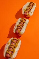 Set of unique hot dogs with mustard. Top view on a orange background.