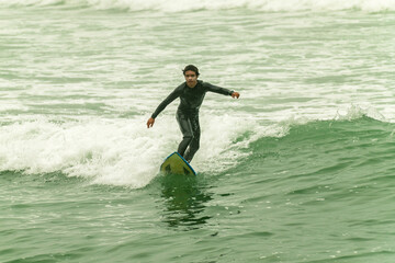 Surfer riding wave in ocean on cloudy morning