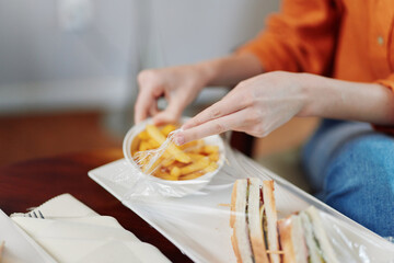A young woman enjoying a healthy meal with fresh sandwiches and fries, emphasizing healthy eating choices in a cozy indoor setting