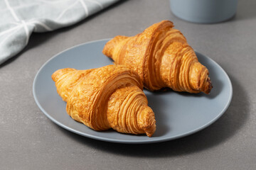 Freshly baked golden croissants on a blue plate ready for breakfast in a cozy kitchen setting