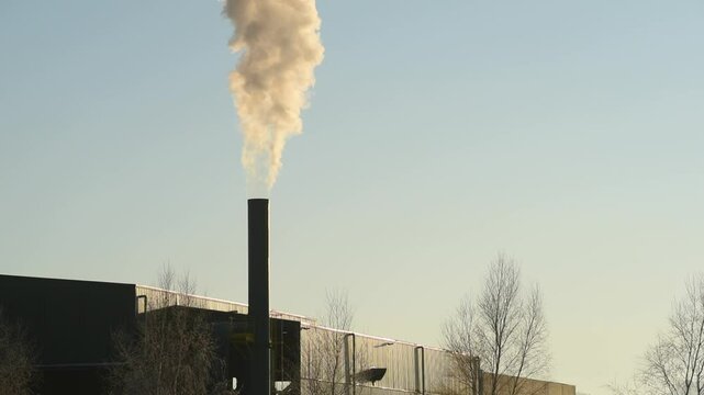 detalle de chimenea de una f&aacute;brica expulsando humo a la atm&oacute;sfera
