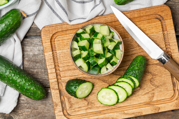 Cucumber on wooden background. Slice of cucumber on background. Fresh organic green cucumbers gherkin. Vegan. Salad ingredient. Farm vegetables. Cut vegetables with knife. Space for text. Copy space