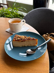 Slice of Caramel Walnut Cheesecake Served with Green Tea in Café Setting. Dessert and Tea Concept. Manual Phone Photography, Selective Focus, No AI